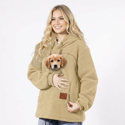 Femme en sweat à poche beige tenant un chiot dans la poche