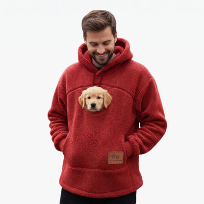 Homme en sweat à poche rouge avec un chiot dans la poche